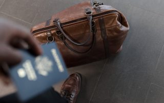 a man holding a passport while his bag is on the ground
